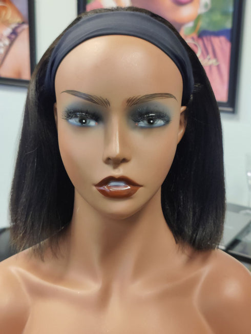 Mannequin head with a black wig and makeup in a blurred indoor setting